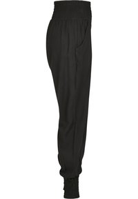 Pantalons de jogging noirs avec taille smockée, poches latérales et bas de jambe fuselés. Fabriqués en tissu léger, à la texture douce et à la coupe décontractée.