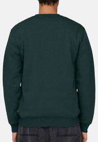 Tumman vihreä collegepaita, jossa on pyöreä pääntie, resorit hihoissa ja helmassa. Silkkinen pinta, jossa on yksinkertainen muotoilu ilman näkyviä logoja tai kuvioita.