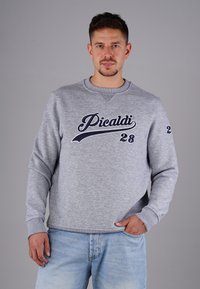 Grau Sweatshirt mit Rundhalsausschnitt und in Marineblau gesticktem Schriftzug "Picaldi 28". Verfügt über lange Ärmeln und gerippte Bündchen, kombiniert mit lässigen Jeans.
