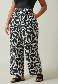 Pantalons larges à motifs noir et blanc avec une taille élastique et des poches latérales, fabriqués à partir d'un tissu léger et texturé.
