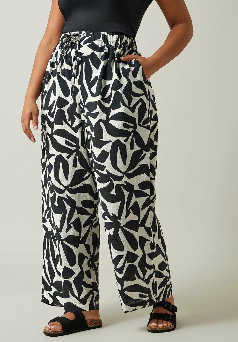 Pantalons larges à motifs noir et blanc avec une taille élastique et des poches latérales, fabriqués à partir d'un tissu léger et texturé.