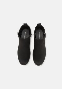 Botas de tobillo negras con un acabado mate suave, punta redonda, cierre de cremallera en el lateral y lengüetas en la parte trasera para facilitar su uso.