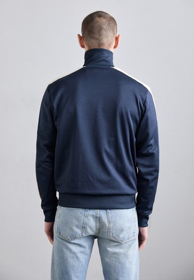 Marinblå sweatshirt med hög krage, ribbad mudd och midja. Har cremefärgade ränder längs axlarna. Mjuk bomullsblandning.