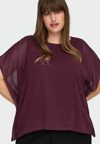 Blusa leggera di colore bordeaux con una vestibilità ampia, maniche larghe e scollo tondo. Tessuto trasparente con una texture liscia.
