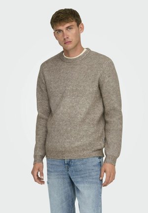 Light brown ribbed sweater with a round neckline and long sleeves. Fabric texture appears soft, paired with light blue distressed jeans.