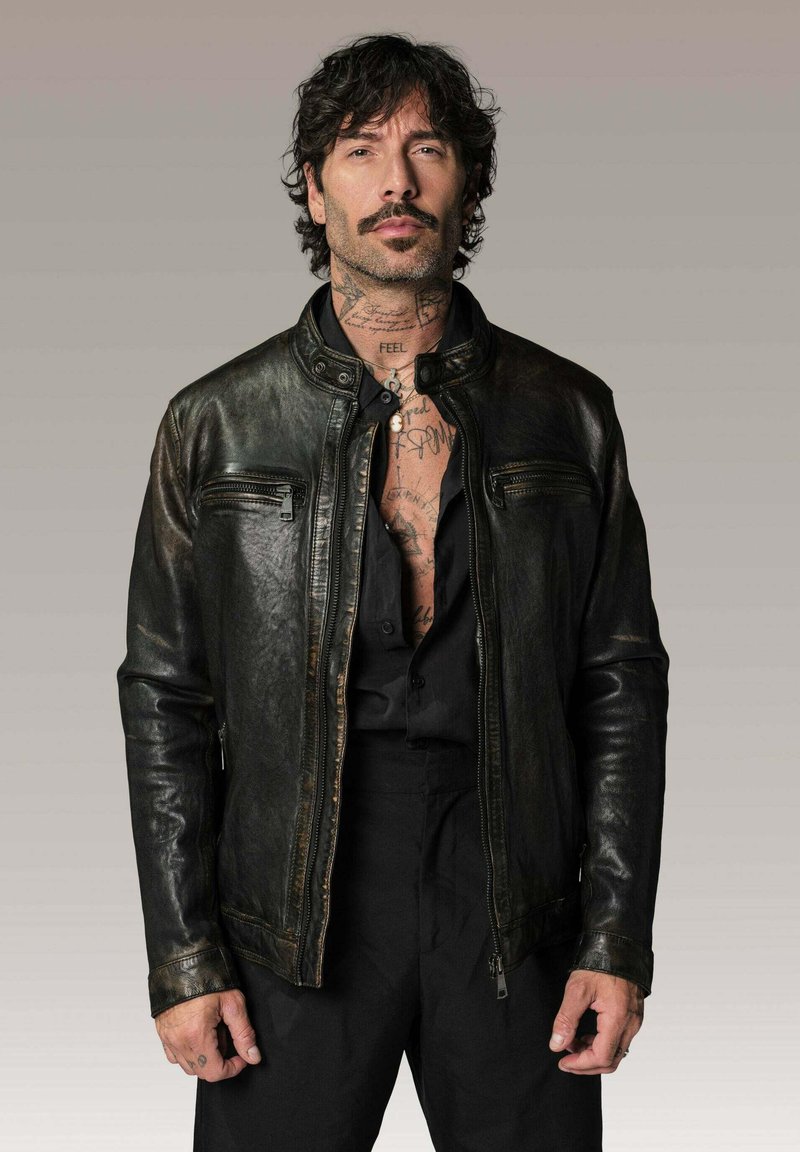 Veste en cuir noir avec un design ajusté, zips proéminents et col montant ; présente une finition texturée et des surpiqûres contrastantes.