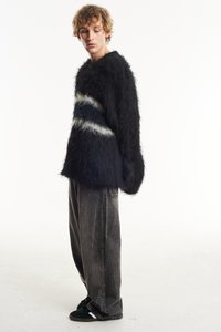 Black fuzzy sweater with a cream and navy striped pattern, paired with loose gray denim pants and black shoes. Textured and oversized fit.