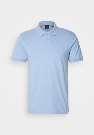 Polo bleu clair en coton. Présente un col classique, deux boutons et un petit patch de logo sur la poitrine. Manches courtes.