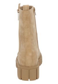 Tan suède enkelboot met een chunky rubberen zool, voorzien van een zijrits en een lus aan de achterkant voor gemakkelijk aan- en uittrekken. Glad textuur, minimalistisch ontwerp.