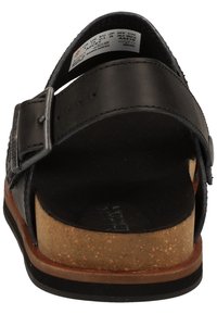 Sandale en cuir noir avec boucle ajustable, semelle intermédiaire en liège et semelle intérieure texturée. La vue arrière met en évidence la forme et les détails de construction.