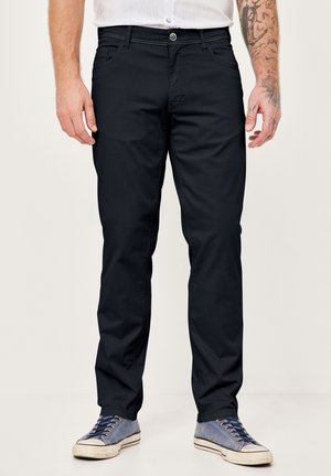Navy blue chinos with a straight-leg cut, featuring front pockets, a zip fly, and subtle stitching details. Paired with blue casual sneakers.