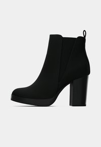 Czarne botki na wysokim obcasie, o gładkiej, teksturowanej powierzchni, z elastycznymi panelami po bokach i zaokrąglonym noskiem. Posiadają solidny, szeroki obcas.