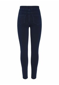 Tamno plave traperice s elastikom u struku, koje imaju dva stražnja džepa i uski kroj. Glatka tekstura bez vidljivih oštećenja.