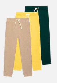 Drei Paar Jogginghosen: beige, gelb und dunkelgrün. Jede hat einen elastischen Bund mit Kordelzug und schmal zulaufende Beine. Weiches Baumwollmaterial.