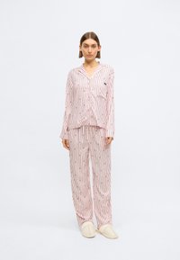 Set de pijamale cu dungi roz, format dintr-un top cu nasturi și pantalonii asortați. Material moale, cu textură ușoară. Prezintă un mic logo pe top.