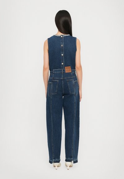Denim jumpsuit met een mouwloos ontwerp, donkere blauwe kleur, witte knoopsluiting aan de achterkant en contrasterende stiksels op zakken en naden.