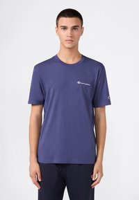 Marineblauwe katoenen T-shirt met korte mouwen, ronde hals en een witte "Champion" logo op de borst en mouw. Glad van textuur.