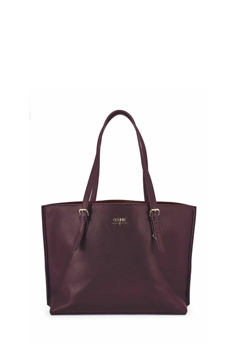 Bordowa torba typu tote z eko skóry z podwójnymi paskami na ramię, zewnętrzną blaszką z logo i usztywnionym kształtem. Teksturowana powierzchnia z akcentami w kolorze złotym.