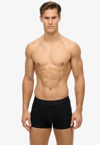 Black stretch boxer shorts with a solid texture, featuring a branded waistband. The fit is close to the body, emphasizing the wearer's shape.