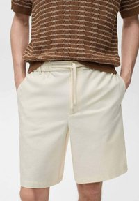 Katoenmengsel, crèmekleurige shorts met een elastische tailleband en koord. Getailleerde pasvorm, knielengte, gladde textuur, minimale details.