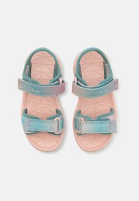 Svetloružové sandále s tyrkysovými popruhmi; nastaviteľné suché zipsy; štruktúrovaná podrážka s geometrickými vzormi; viditeľné meno značky "Clarks".
