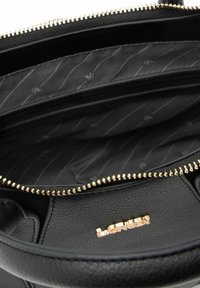 Interno di borsa in pelle nera con tessuto strutturato, scomparti multipli e dettagli in metallo dorato. Internamente con marchio "La Redi".