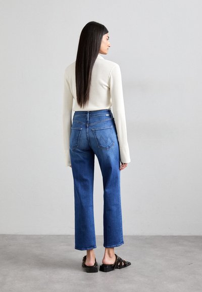 Waffle-knit cream long-sleeve top paired with high-waisted blue denim jeans, featuring straight legs and back pockets. Black sandals complete the look.