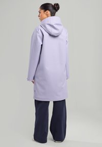 Light purple waterproof coat featuring a hood, long sleeves, and a long silhouette, paired with navy loose-fit pants.