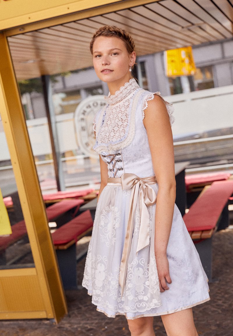 Weißes Spitzenkleid mit kurzen Ärmeln, floralen Stickereien, einem Satinband-Gürtel und Korsett-Details auf dem Rücken. Glatte Stoffstruktur.
