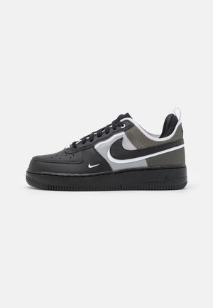 Baskets basses Nike Air Force 1 noires, blanches et grises avec semelle noire, logo Swoosh blanc et matériaux en mesh et cuir.