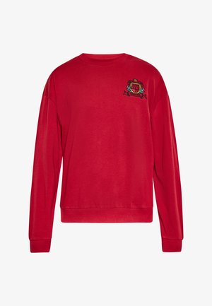 Red sweatshirt with a round neck, long sleeves, and ribbed cuffs. Features an embroidered emblem on the chest. Smooth texture.