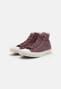 Sneakers înaltă în nuanță mauve din pânză cu tălpi și șireturi albe. Prezintă ochiuri argintii și vârfuri texturate pentru aderență.