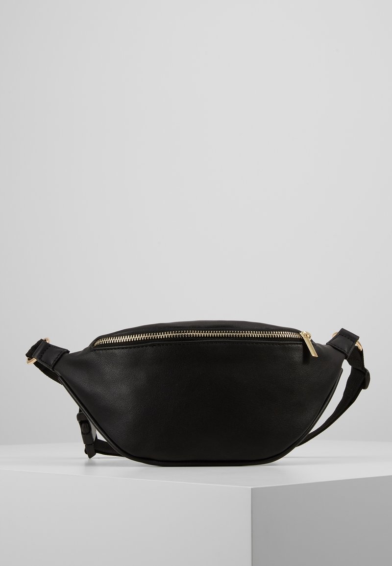 Sort læder bæltetaske med en buet form, guld lynlås og justerbar rem. Glat overflade og minimalistisk design.