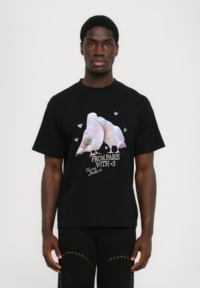 Zwarte katoenen T-shirt met een afbeelding van twee duiven in pastelkleuren en harten, de tekst luidt: "VAN PARIJS MET <3" in het wit.