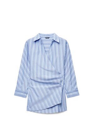 Blusa azzurra chiaro a maniche lunghe con scollo portafoglio, righe verticali bianche e blu più scuro e colletto appuntito su sfondo bianco.