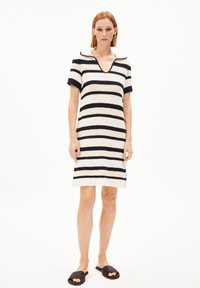 Stickad klänning med marinblå och vita horisontella ränder, korta ärmar, V-ringning och A-linjeformad siluett. Kompletterad med svarta slidesandaler.