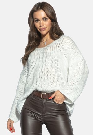 Lekko dziergany biały sweter z szerokimi rękawami, połączony z brązowymi skórzanymi spodniami. Szczegóły obejmują okrągły dekolt i luźny krój.