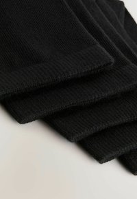 Fekete zoknik puha, bordázott anyagból, szépen egymásra rakva. Az anyag sima tapintású, véggel ellátott élekkel és látható minták nélküli.