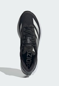 Fekete sportcipő texturált kötött felsőrésszel, fehér csíkokkal és fekete fűzőkkel. Párnázott talpa van a támasz és kényelem érdekében.