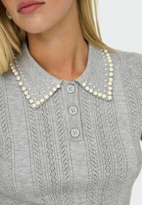 Maglietta grigia in maglia con una patta di bottoni, motivo testurizzato e un colletto decorato con perle e piccoli borchiette.