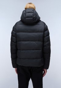 Svart puffjacka med huva, med horisontell söm, vadderad textur och elastiska ärmslut, som bärs av en person sedd bakifrån.