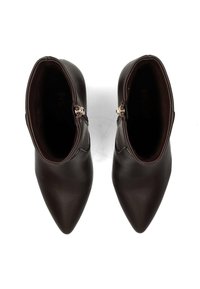 Bottes en cuir marron jusqu'à la cheville avec un bout pointu, une texture lisse et des fermetures éclair latérales. La vue de dessus met en valeur l'intérieur et les détails de conception.