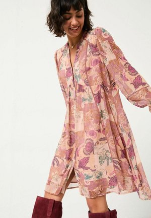 Blumenkleid in sanftem Rosa mit lila und türkisfarbenen Mustern, mit Glockenärmeln und einem V-Ausschnitt. Enthält seitliche Schlitze und ein lockeres, fließendes Design.