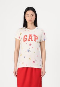 Kreminės spalvos trumpomis rankovėmis marškinėliai su raudonu "GAP" logotipu ir gėlių raštu rožinės, mėlynos ir geltonos spalvų. Minkšta medvilnė, standartinio kirpimo.
