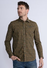 Donkergroene blouse met lange mouwen en een abstract patroon in oranje en bruin. Voorzien van een klassieke kraag en een knopenlijst voor de sluiting.