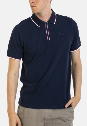 Polo-shirt marine avec col zippé, présentant des rayures accentuées rouges et blanches, fabriqué en tissu lisse, avec un logo discret sur la poitrine.