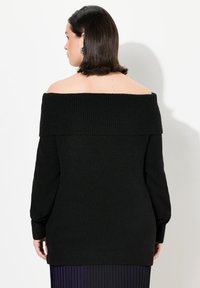 Schwarzer, gerippter, schulterfreier Pullover mit langen Ärmeln, der einen weiten Ausschnitt und strukturierten Stoff aufweist. Ansicht von hinten hervorgehoben.