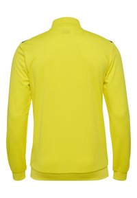 Gul langærmet top med krave, tekstureret stof og sorte detaljer på skuldrene. Bagfra ses en glat overflade.