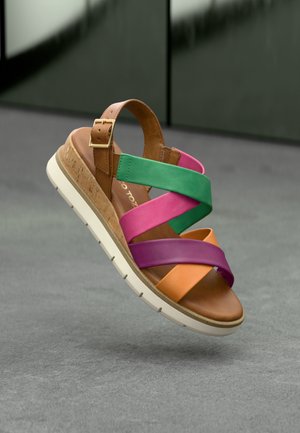 Brown leather sandal with multicolored straps in pink, green, purple, and orange. Features a cushioned footbed and white rubber sole.
