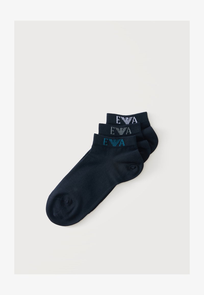 Trois paires de chaussettes noires montantes empilées, chacune avec un logo et un texte de couleur différente près du bord-côte.